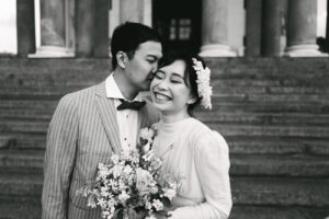Coppia di sposi, lei che sorride con i fiori in mano